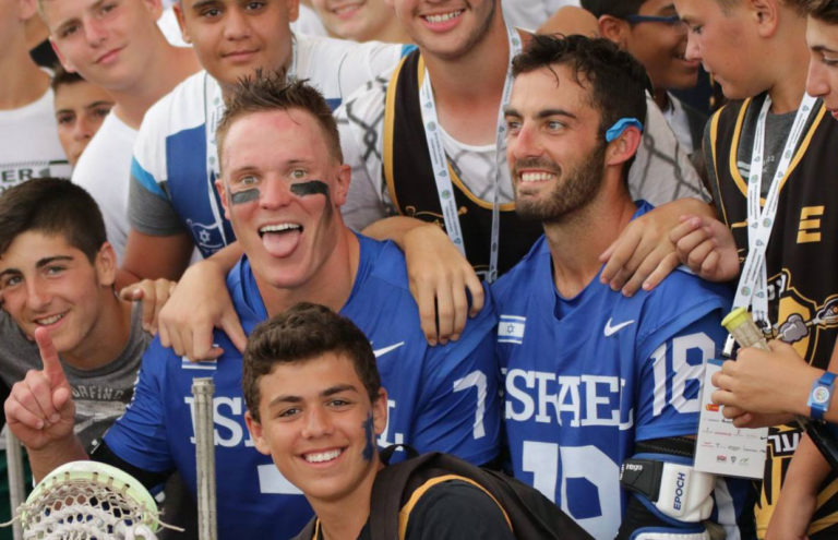 Jacob Silberlicht (left) and Seth Mahler (right) celebrate a World Championship opening night win with Israel fans and youth lacrosse players at Netanya Stadium.